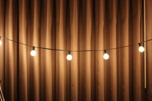 Cozy warm string lights illuminating a brown draped curtain for soft ambient lighting.